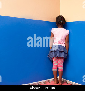 Enfant debout dans l'angle, face au mur Banque D'Images