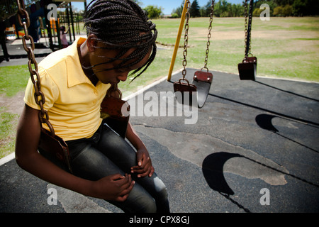 Une petite fille assise sur une balançoire à la triste Banque D'Images