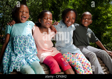 Quatre enfants assis sur un journal dans un parc Banque D'Images