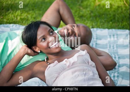 Un jeune couple africain portant sur une couverture dans un parc Banque D'Images