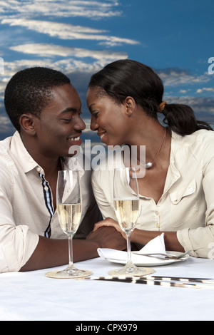 Un Africain couple chatting et boire du champagne en plein air pendant le coucher du soleil Banque D'Images