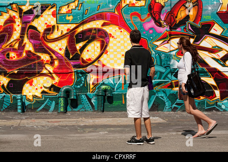 United States, New York City, Queens, Crane Street, new-yorkais d'examiner une partie de l'écriture Graffiti Banque D'Images