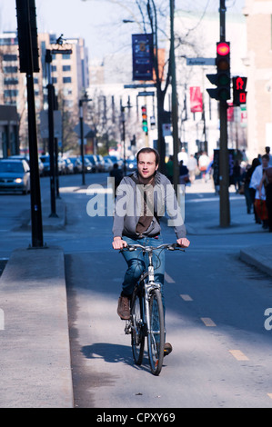 Jeune homme de faire du vélo sur une piste cyclable au centre-ville de Montréal, province de Québec, Canada. Banque D'Images