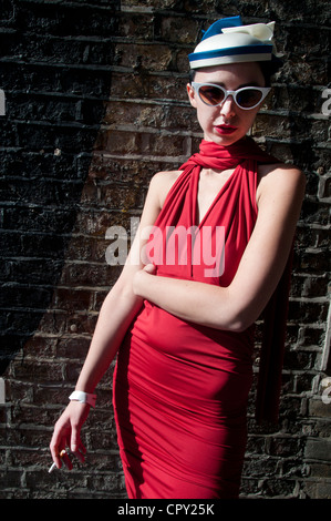 Parti Rivington Street, Shoreditch, London. Jeune femme vêtue de rouge, bleu et blanc de fumer une cigarette. Banque D'Images