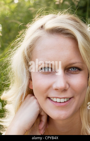 Très belle jeune femme blonde en souriant et regardant la caméra. Piscine d'été contre un portrait flou fond vert. Banque D'Images