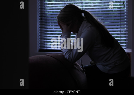 Profil d'une fille avec une queue de cheval, assis mains couvrant son visage. Silhouette. Banque D'Images