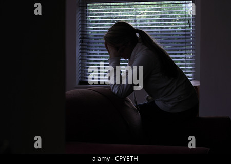 Profil d'une fille avec une queue de cheval, assis mains couvrant son visage. Silhouette. Banque D'Images