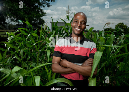 Jeune homme noir se dresse parmi certaines cultures, smiling at camera Banque D'Images