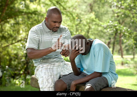 Père et fils africains assis dehors dans un jardin Banque D'Images