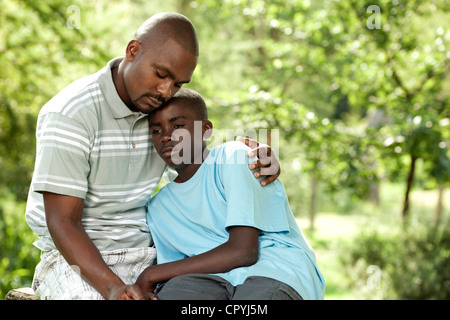 Père et fils africains assis dehors dans un jardin Banque D'Images