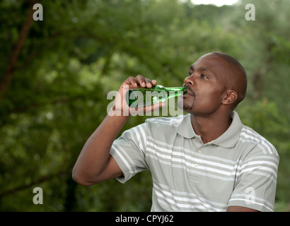 L'homme africain se trouve en dehors de boire une bière Banque D'Images