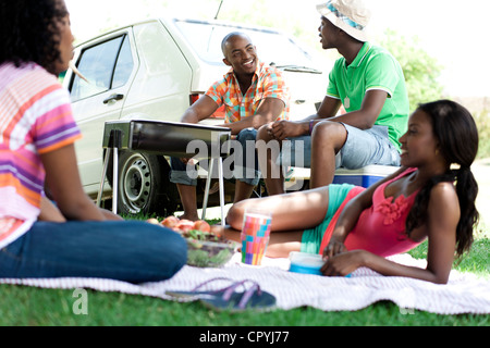 Quatre jeunes amis noirs braaing la viande dans un parc Banque D'Images