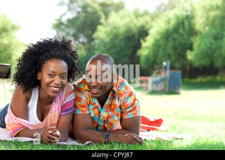 Jeune black couple lying in a park, smiling at camera Banque D'Images