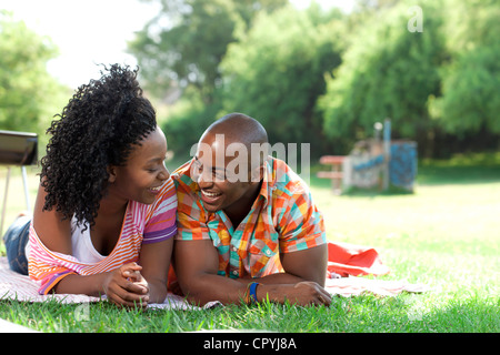 Jeune black couple lying in a park, smiling at each other Banque D'Images