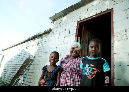 Une femme africaine et ses deux enfants se tiennent à l'extérieur de leur foyer rural Banque D'Images