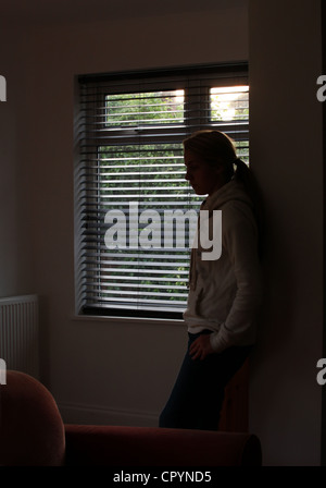 Profil d'une fille avec une queue de cheval, regarder par la fenêtre. Silhouette. Banque D'Images