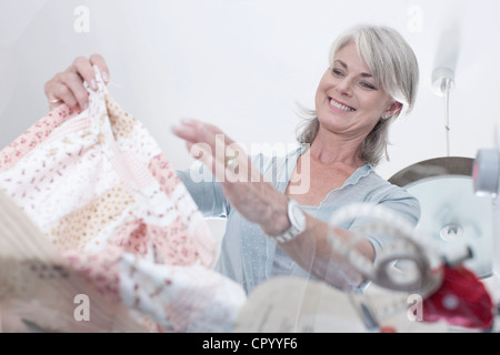 Femme plus âgée pour coudre un tissu de collecte Banque D'Images