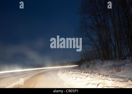 Une longue exposition de voiture sur snowy rural road Banque D'Images