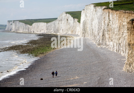 UK. L'Angleterre. Kent. Eastbourne. Falaises de craie et de couple en train de marcher le long d'une plage de galets. Banque D'Images