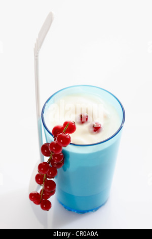 Coupe bleu et blanc cuillère en plastique avec du yogourt et de groseille rouge Banque D'Images