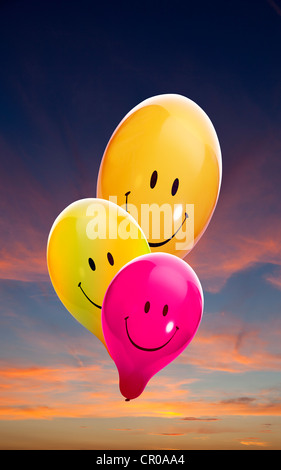 Trois ballons smiley coloré, coucher du soleil à l'arrière Banque D'Images