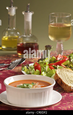 Un lieu idéal pour le déjeuner de soupe à la tomate et salade verte avec du pain et un verre de vin, huiliers de l'huile et le vinaigre. Banque D'Images