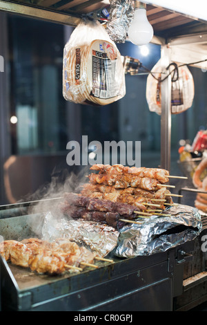 Un vendeur alimentaire chariot sert des grillades de shish kebab dans la nuit dans la ville de New York. Banque D'Images