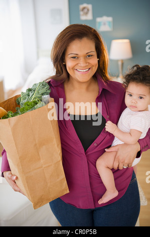 Mixed Race mother holding baby et épicerie Banque D'Images