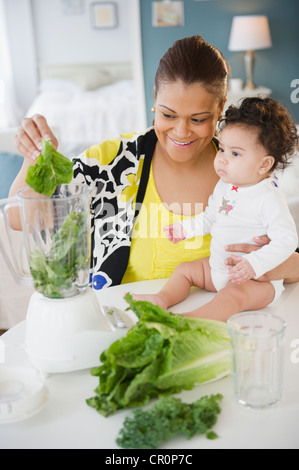 Mixed Race mother holding baby et en utilisant blender Banque D'Images