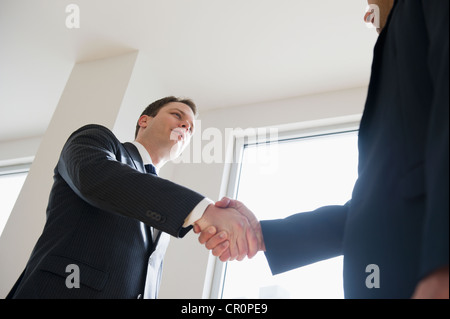 Businessmen shaking hands in office Banque D'Images