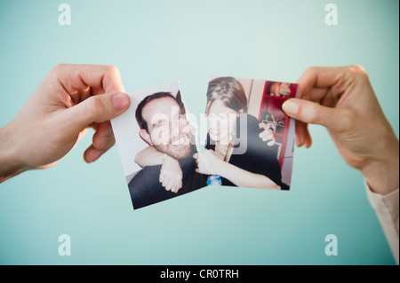 Close up of man's woman's hands holding et photographie déchirée d'eux-mêmes, studio shot Banque D'Images