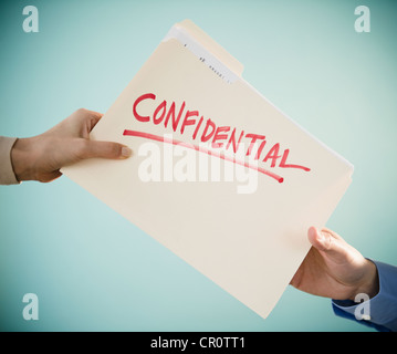 Close up of man's et Woman's hands holding document confidentiel, studio shot Banque D'Images