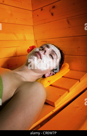 Jeune femme avec masque facial dans le sauna Banque D'Images