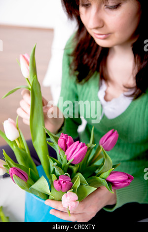 Jeune femme organisation de tulipes dans un vase Banque D'Images