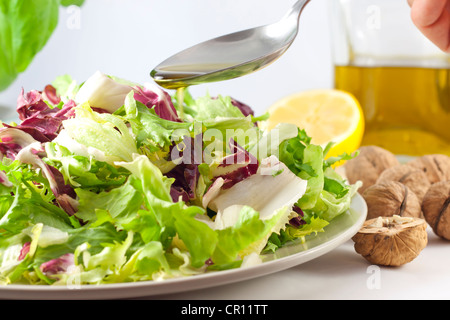 Salade de légumes et versez de l'huile Banque D'Images