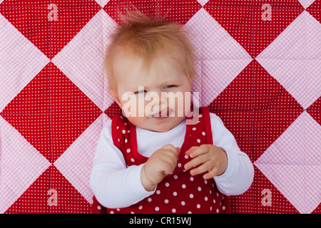 Fille, 8 mois, couché sur une couverture Banque D'Images