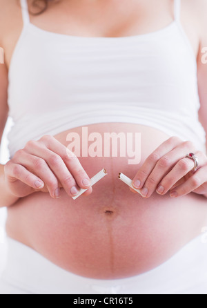 USA, New Jersey, Jersey City, pregnant woman holding broken cigarette Banque D'Images