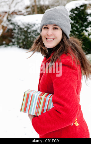 Woman wrapped gift in snow Banque D'Images