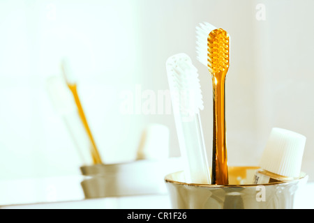 Brosses à dents et du dentifrice dans un verre en face d'un miroir Banque D'Images