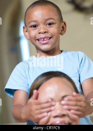 Smiling boy couvrant les yeux des mères Banque D'Images