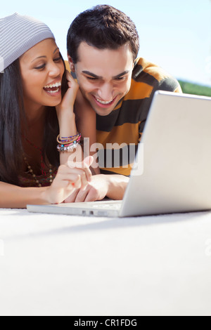 Smiling couple using laptop outdoors Banque D'Images