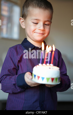 Boy holding gâteau miniature avec des bougies Banque D'Images