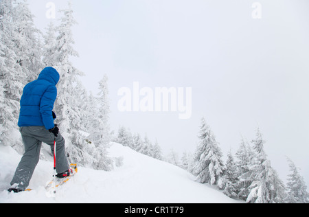 L'homme la raquette sur snowy hillside Banque D'Images
