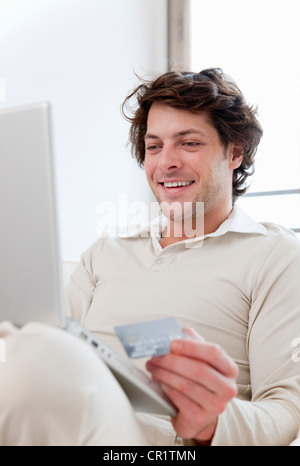 Man shopping online in living room Banque D'Images