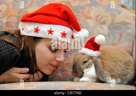 Jeune fille et un nain européen Lapin (Oryctolagus cuniculus) wearing Santa hats Banque D'Images