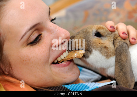 Girl eating un biscuit avec un nain européen Lapin (Oryctolagus cuniculus) Banque D'Images