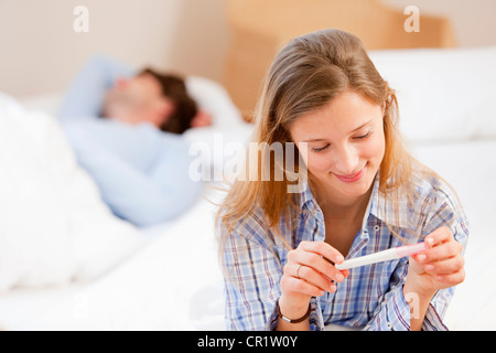 Woman Reading test de grossesse on bed Banque D'Images