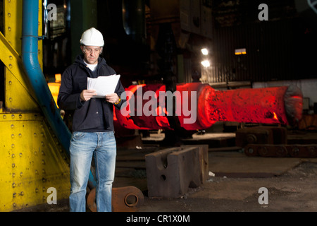 Worker reading papers en acier forge Banque D'Images