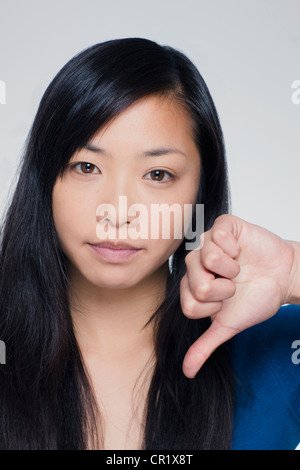 Studio portrait of young woman showing Thumbs down sign Banque D'Images