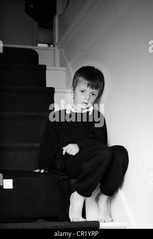 Seul enfant assis sur les escaliers. Banque D'Images